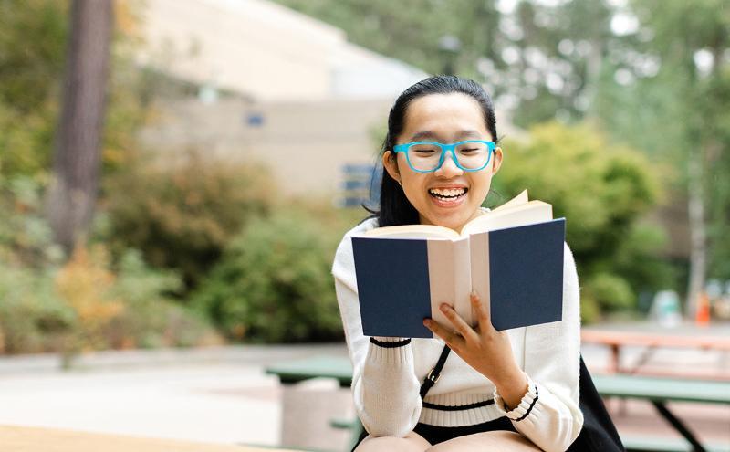 capilano university student sitting in the library reading